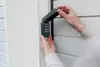 A person's hands are shown opening the cover of a wireless keypad for a garage door opener. Produktbild-Vorschau