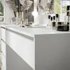 A close-up view of a white dresser with several cosmetic products on its surface. Náhled obrázku produktu