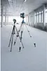 Two laser levels on tripods in a large, empty, modern building with concrete pillars and large windows. Voir les images du produit