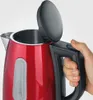 A close-up shot of a person's hand holding a red electric kettle. Anteprima dell’immagine prodotto