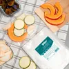 A collection of food items, including sliced pumpkin, zucchini, and plums, are arranged on a checkered cloth next to a package of Sillar vacuum sealing bags. Náhľad obrázku produktu
