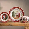 A set of Christmas-themed tableware, including two plates and a mug, displayed on a wooden surface. Voir les images du produit