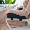 A person's arms resting on chair armrest cushions while sitting at a desk. Náhled obrázku produktu