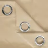 A close-up view of a beige fabric with three metal grommets. Náhled obrázku produktu