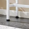 A close-up view of the white metal legs of a console table, resting on a dark wood-like floor with a rug partially visible. Anteprima dell’immagine prodotto