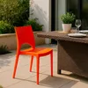 An orange chair is placed next to a brown wicker table on a patio. Voir les images du produit