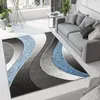 A modern living room with a gray sofa and a rug with a wave pattern in gray, black, and blue. Náhľad obrázku produktu
