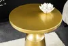 A close-up shot of a round, gold-colored side table with a decorative lotus-shaped object on top. Produktbild-Vorschau