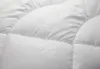 A close-up view of a white quilted comforter with a subtle fleur-de-lis pattern. Produktbild-Vorschau