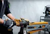 A person is using a reciprocating saw to cut wood on a workbench. Voir les images du produit