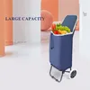 A blue shopping trolley filled with groceries, set against a minimalist background with abstract shapes and text. Produktbild-Vorschau