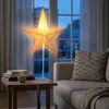 A star-shaped lamp is placed on a small table next to a sofa in a dimly lit room. Voir les images du produit