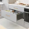 An open kitchen drawer filled with glass jars containing various food items. Produktbild-Vorschau