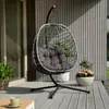 A hanging egg chair with a gray cushion is placed on a wooden deck next to a house. Produktbild-Vorschau