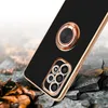 A black phone case with a gold ring and camera housing is shown on a cracked, rocky surface with fallen leaves. Produktbild-Vorschau