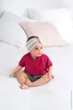 A baby sitting on a bed. Produktbild-Vorschau
