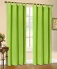 A pair of bright green curtains hangs in front of a window, with a small table and vase of flowers to the left. Produktbild-Vorschau