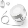 A Philips Hue Iris table lamp with its accessories, including a power adapter and plug adapters, laid out on a white background. Produktbild-Vorschau