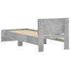 A simple bed frame with a concrete-gray finish, shown from the side against a white background. The bed frame has a headboard and a slatted base. Podgląd zdjęcia produktu