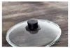 A close-up shot of a glass pot lid with a black handle resting on a wooden surface. Náhled obrázku produktu