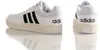 Two views of a pair of white Adidas sneakers with black stripes and cream-colored soles, shown against a white background with reflections. Anteprima dell’immagine prodotto