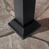 A close-up view of the base of a black metal post, possibly part of a gazebo or pergola, resting on a stone patio. Podgląd zdjęcia produktu
