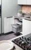 A modern kitchen scene with an open cabinet revealing a pull-out trash bin system. Produktbild-Vorschau