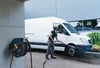 A man is washing a white van with a hose reel attached to a concrete pillar. Produktbild-Vorschau
