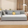 A gray upholstered daybed with several pillows is shown in a room with a window and a lamp. Produktbild-Vorschau