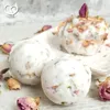 Three bath bombs with dried rose petals and buds, arranged on a white surface with scattered dried roses. Produktbild-Vorschau