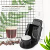 A coffee capsule adapter next to a glass of coffee and coffee beans, with decorative plants in the background. Produktbild-Vorschau