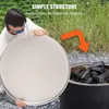 A person is holding a round metal lid over a fire pit filled with charcoal. Produktbild-Vorschau
