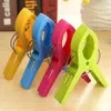 Four colorful plastic clothespins are lined up on a wooden surface. Produktbild-Vorschau