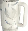 Close-up of a white travel mug with a floral pattern. Voir les images du produit