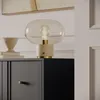 A modern interior scene featuring a black and gray dresser with a decorative lamp on top. Produktbild-Vorschau