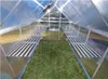 Interior view of a greenhouse with metal shelving and a grass floor. Náhľad obrázku produktu
