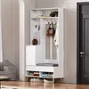 A white entryway storage unit with a bench and shoe shelves, placed next to a door. Produktbild-Vorschau