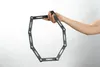 A hand holding a black folding bicycle lock against a white background. Produktbild-Vorschau