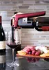 A person is pouring red wine from a bottle into a glass using a wine opener. A cheese and charcuterie board is in the background. Voir les images du produit
