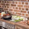 A kitchen counter with a glass stove top cover featuring a floral design, a frying pan, and various vegetables. Náhľad obrázku produktu