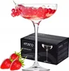 A champagne coupe glass filled with a drink and berries, next to its packaging box and strawberries. Produktbild-Vorschau