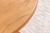 A close-up view of the edge of a wooden table with a textured rug in the background. Produktbild-Vorschau
