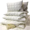 A stack of white, quilted pillows with a label on each. Produktbild-Vorschau