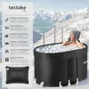 A woman is sitting in an ice bath on a balcony overlooking a snowy landscape. Náhled obrázku produktu