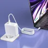 A white laptop charger and cable plugged into a wall socket, connected to a laptop. Podgląd zdjęcia produktu