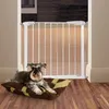 A dog is lying on a cushion in front of a white baby gate. Voir les images du produit