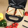 A sandwich maker with two sandwiches inside, surrounded by fresh vegetables and tomatoes on a wooden surface. Náhľad obrázku produktu