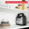 A compact grill is stored on a shelf in a kitchen cabinet, alongside plates and jars of food. Podgląd zdjęcia produktu