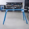 A blue metal stand for tools or machinery is set up in a workshop with tools on a pegboard in the background. Anteprima dell’immagine prodotto
