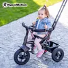 A young child sits in a tricycle outdoors on a paved path. Produktbild-Vorschau